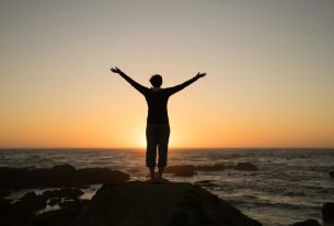 Silhouette of a person with arms raised at sunset