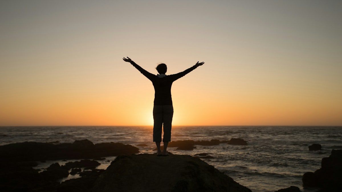 Silhouette of a person with arms raised at sunset
